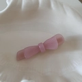 Primer plano detallado de un clip de pelo con lazo rosa en un plato de concha blanca - Rosa