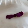 Detail view of a double-layered acetic acid purple bow hair clip on a white shell plate - Deep purple