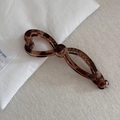 Macro shot of dark brown translucent tortoiseshell banana clip with hollow bow design - Hollow Bow Banana Clip - Transparent Tortoiseshell