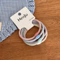 Close-up of 5-piece macaron colored elastic hair bands with frosted beads on a wood desk - Basic Texture