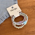 Macro shot of colorful macaron-toned hair bands with plastic beads on display card - Embossed Texture