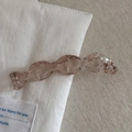Gros plan d'une pince à cheveux en acrylique translucide marron sur tissu texturé - Champagne
