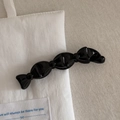 Dettaglio del fermaglio banana nero lucido con design a fiocco segmentato su tessuto - Nero