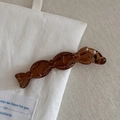 Dettaglio del fermaglio per capelli marrone a forma di caramella su tela bianca - Caffè Trasparente