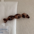 Détail d'une pince à cheveux en résine marron foncé avec texture ambre sur tissu - Écaille Transparente