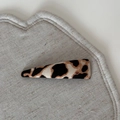Detailed view of a triangular leopard print hair clip on a soft beige fabric surface - Beige Coffee Leopard - Triangle Clip
