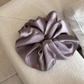 Détail d'un chouchou en satin violet poudré avec un petit médaillon doré gravé du logo - Gris Violet