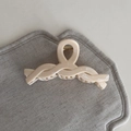 Detail view of the twisted rope design on a glossy cream hair claw clip with gold spring - Braided Style