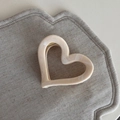 Macro view of cream heart-shaped hair claw with marble texture and golden spring detail - Heart Style
