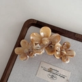 Détail d'une pince à cheveux fleurs avec texture ambre marbrée sur plateau lin - Style de Trois Fleurs Ambré