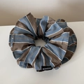 Détail d'un chouchou rayé surdimensionné avec motifs bleu et marron et étiquette en tissu - Bleu Café