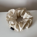 Nahaufnahme vom beige-weiß gestreiften Haargummi mit schwarzem Mode-Etikett-Detail - Beige