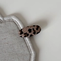 Close-up detail of leopard print fabric hair clip on beige linen textured display pad - Leopard Wide Oval Clip