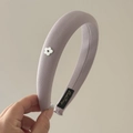 Primer plano de diadema acolchada lila con textura de tela y detalle de flor de metal - Morado