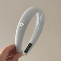 Primer plano de diadema de tela azul claro con detalle de flor blanca y textura suave - Azul