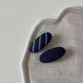 Detail view of navy blue striped and solid twill fabric oval BB hair clips on linen - Striped Navy Short Oval