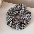 Detailaufnahme des schwarz-weiß karierten Haargummis mit roten Kirschstickereien - Schwarzer Gingham Haargummi