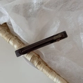 Close-up of handmade dark brown acetate hair clip with France label in a woven basket - Gray
