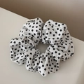Dettaglio dello scrunchie floreale bianco con stampa nera ed etichetta del marchio cucita - Stile Floreale Bianco