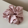 Detail shot of a large pink satin scrunchie showing smooth texture and brand label - Shimmer Scrunchie / Pink