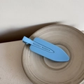 Close-up of a matte light blue seamless hair clip on a minimalist ceramic plate - Blue