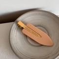 Close-up of matte pink seamless hair clip placed on a minimalist ceramic plate - Orange