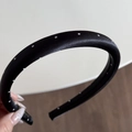 Close-up of a wide padded headband featuring classic black satin with white polka dots - Narrow Headband / Black