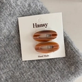 Detail view of two oval tortoise shell hair clips on a minimalist white display card - Milk Coffee