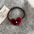 Dettaglio dell'elastico per capelli a cuore rosso con fiocco nero e scritte oro - Rosso
