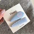 Detail of blue matte resin hair clips with pink smiley face and stitch patterns - Blue