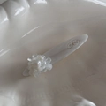 Detailed macro view of white flower hair clip with SAN engraved logo on resin base - White