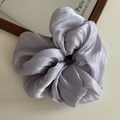 Detailed view of lavender purple satin scrunchie with pleated texture and pearly luster - Purple