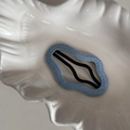 Detail of light blue denim fabric hair clip with black wavy metal grip on ceramic tray - Light Blue Denim-Cloud