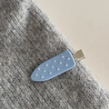 Dettaglio di un fermaglio azzurro con perline bianche su una morbida trama grigia a maglia - Tipo Senza Cuciture a Pois Blu