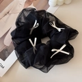 Detail eines schwarzen Tüll-Haargummis mit weißen Schleifen auf einem Modemagazin - Schwarz