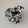 Dettaglio di scrunchie a scacchi bianchi e neri con trama a pieghe e bordo grigio - Scrunchie / Grigio