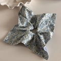 Vue détaillée du chouchou floral bleu clair sur table blanche avec assiette - Floral Bleu Anneau Carré