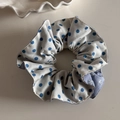 Détail d'un chouchou à pois bleus et fleurs violettes sur un plateau blanc - Pois Bleus Anneau de Taille