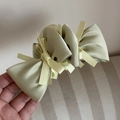 Detail of light green tiered satin bow hair claw clip showing silk texture and layers - Green