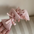 Close-up of pink satin bow hair claw clip showing layered ribbon texture and smooth silk finish - Pink