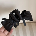 Detail view of a black layered satin bow hair claw clip with a glossy silk texture - Black