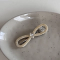 Detailed macro view of cream acetate infinity bow hair clip with rhinestone and engraving - Rice Apricot