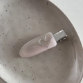 Détail d'une pince à cheveux en acétate rose avec cœur en strass sur plateau - Rose