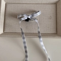 Detail van de zwart-witte geruite haarstrikclip met lange linten op beige linnen textuur - Zwart-wit geruit