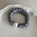 Close-up of silver-grey satin scrunchie with large pearl detail in a white porcelain dish - Fog Blue