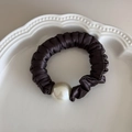 Detail of a brown satin scrunchie featuring a large elegant pearl on a white plate - Dark Coffee
