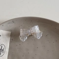 Detail view of a translucent acetate bow hair clip with hollow dot pattern in ice blue - White