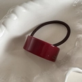 Detail view of burgundy acetate rectangle charm with France Handmade text on hair tie - Red