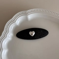 Détail d'une barrette noire ovale avec cœur argenté sur plateau en céramique blanc - Noir Pailleté