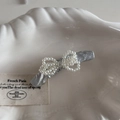 Dettaglio di un fermaglio per capelli argento glitterato con perle su piatto a conchiglia - Tessuto Increspato Argento - Forcina Curva
